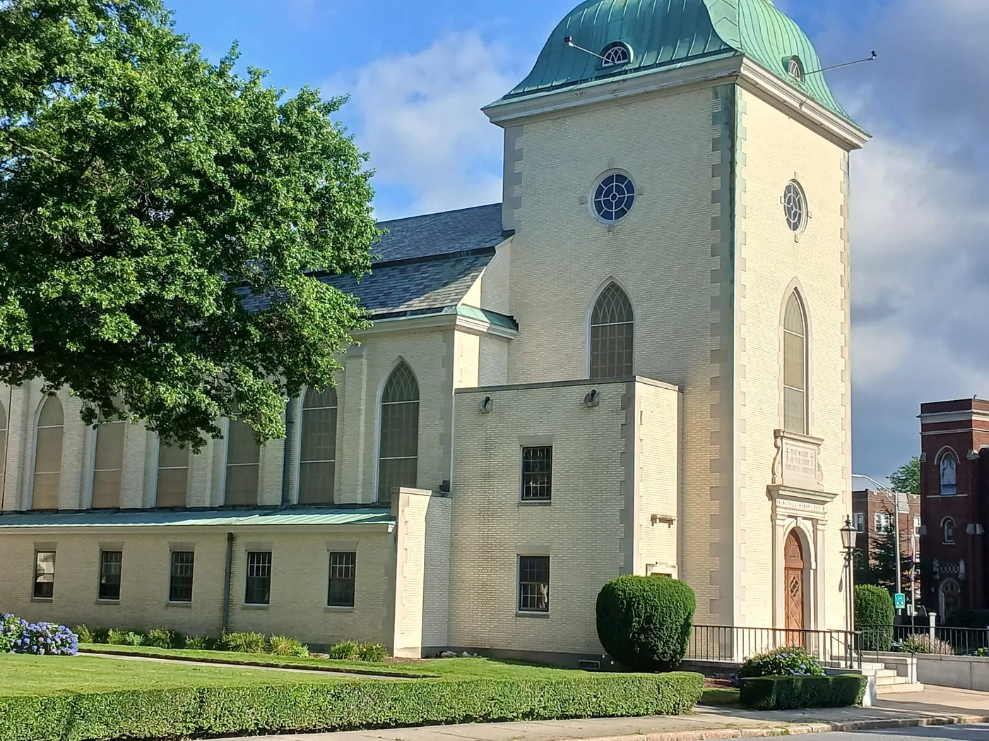 Painted cream brick church exterior with green roof